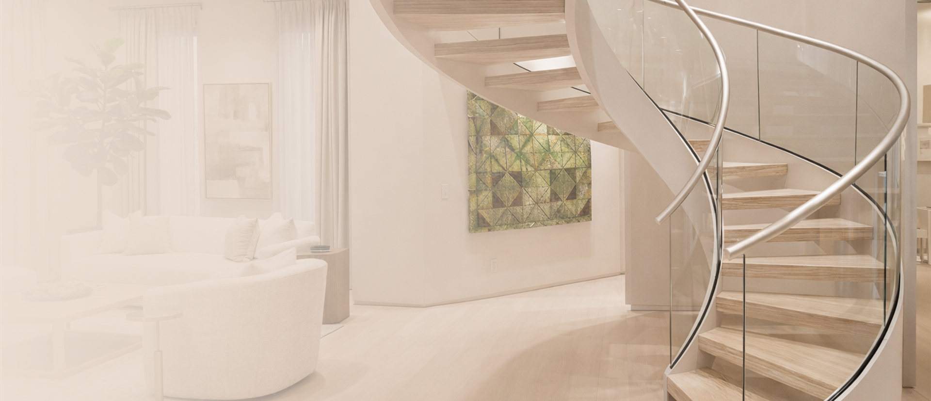 Curved floating staircase with stainless steel and glass railings in a bright modern home